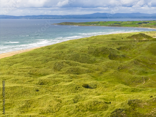 Aerial view of the green sand dunes of Finner overlooking the sandy beach and Atlantic Ocean in County Donegal, Ireland.