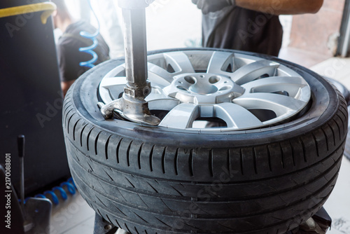 Tire mounting service with mechanic fitting rubber onto alloy rim using tire changer, automotive workshop maintenance for replacement, wheel repair and safe driving.