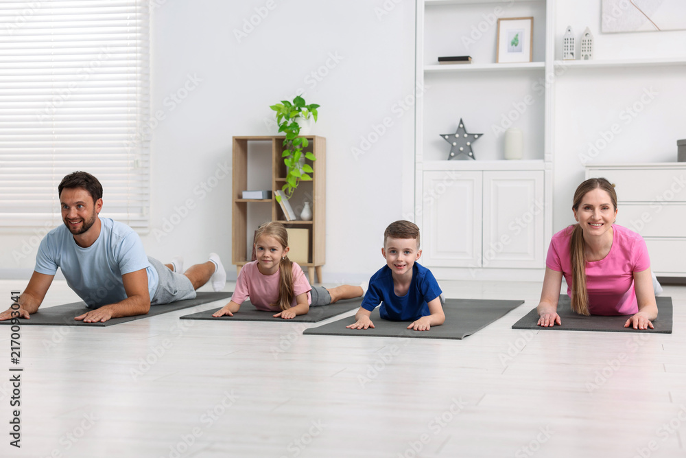 Fototapeta premium Happy family doing exercise together at home