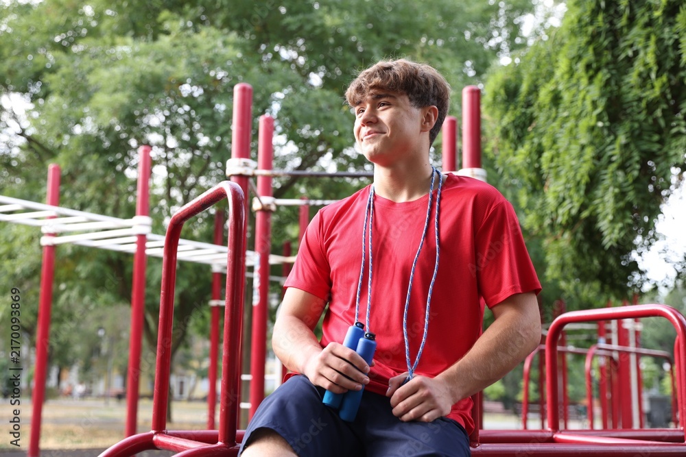 Fototapeta premium Teenage boy with jumping rope at outdoor sports ground. Space for text