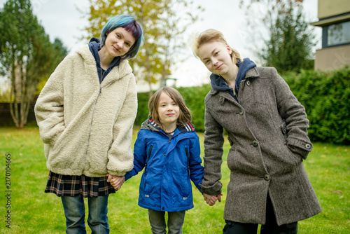 Canvastavla Three siblings pose together outdoors on a chilly autumn day, with a smiling boy hugging his older sister