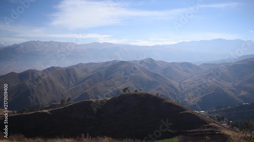 Panoramic view of mountains overlooking a distant city against a cloudy sky in Cusco, Peru.