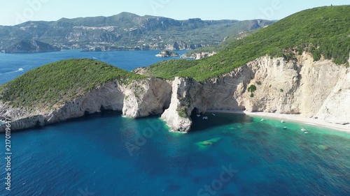 Aerial high‑angle static shot of Chomi Beach with turquoise water, anchored boats, and white cliffs near Paleokastritsa, Corfu, Greece