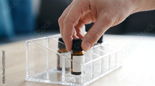 Hand picking an essential oil bottle from a transparent plastic organizer