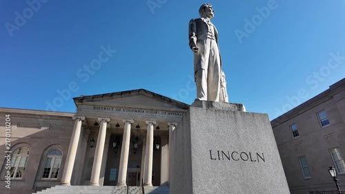 Tilt up to the Abraham Lincoln statue standing outside the District of Columbia Court of Appeals building in Washington, DC, under a clear blue sky. 15341  