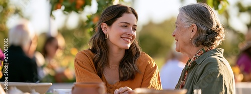 Happy granddaughter and grandmother enjoy meal together at outdoor table