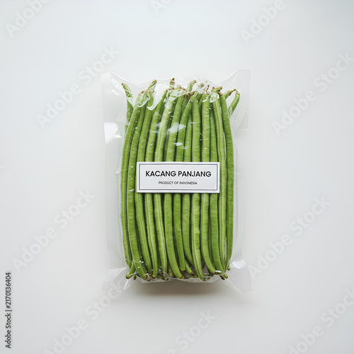 Fresh long beans (Kacang Panjang) in transparent plastic packaging with label, product of Indonesia, isolated on white background.