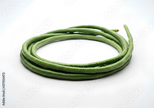 Fresh coiled yardlong beans isolated on white background, organic long bean or snake bean used as a healthy cooking ingredient.