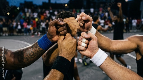 Basketball team celebrates victory with a fist bump huddle on outdoor court