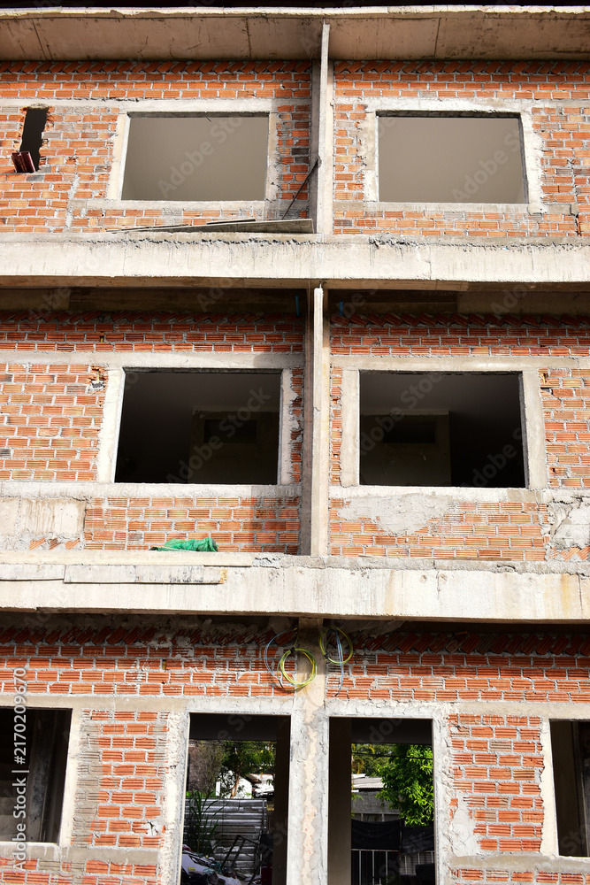 Naklejka premium exterior view of brick house under construction with concrete structure
