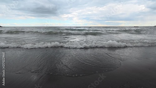 Lake Ontario waves washing upon sand beach under cloudy sky in Bluffer's Park, Scarborough, Toronto, Canada