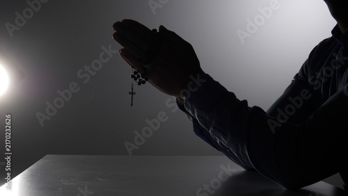 Foto Silhouette of person clasping rosary and cross in prayer, seeking solace and spi