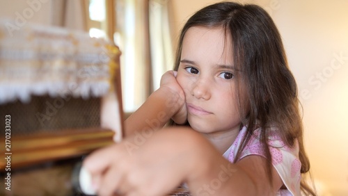 Foto Young girl resting her head on her hand, looking with a sad and apathetic expres