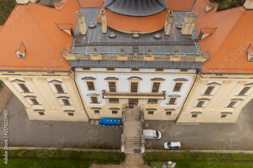 Aerial view of the historic Slavkov Castle featuring its distinctive orange tiled roof, symmetrical facade, and stone entrance staircase in Slavkov u Brna, South Moravian Region, Czechia.