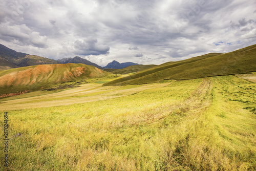 Fotografía A natural landscape of rolling grasslands, colorful hills, and distant mountains under a cloudy sky