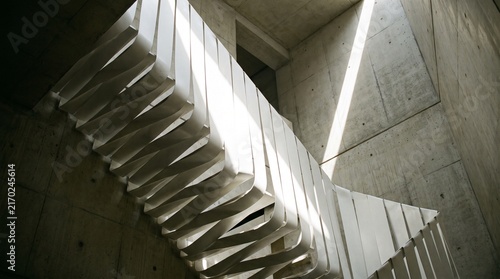 Modern concrete staircase with unique folded balustrade and natural light patterns