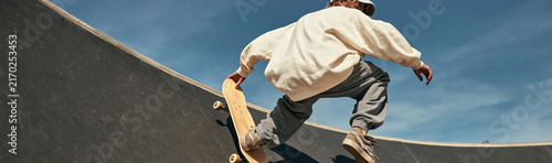 Skateboarder's Airtime: A young person performs a dynamic skateboarding trick, catching air within a concrete skatepark under a clear blue sky.