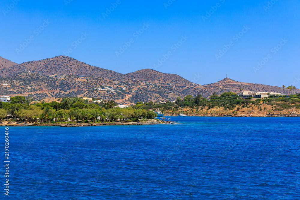 Fototapeta premium Coastal view with deep blue water, greenery, and rocky hills