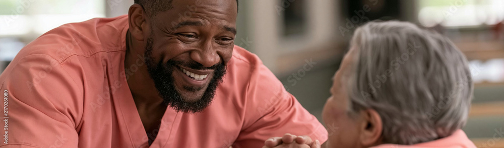 Fototapeta premium Caring Interaction: A kind caregiver shares a heartwarming moment of laughter with an elderly patient, highlighting the importance of human connection and empathy in caregiving.