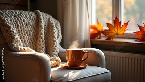 Steaming coffee cup on armchair with knit blanket