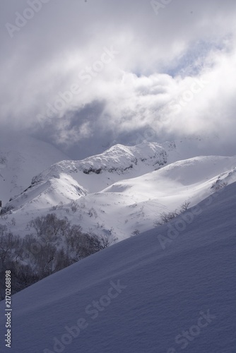 Obraz na plátne Clouds racing over a snowy mountain ridge in winter, Hokkaido, Japan