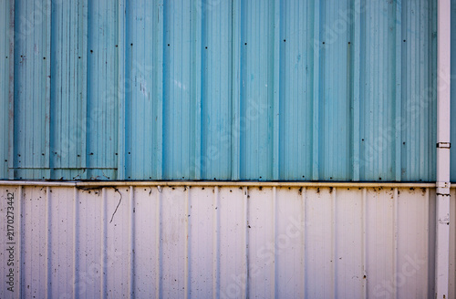 Obraz na plátne Industrial blue corrugated metal siding background texture with a white lower panel and slight rust staining along the seam