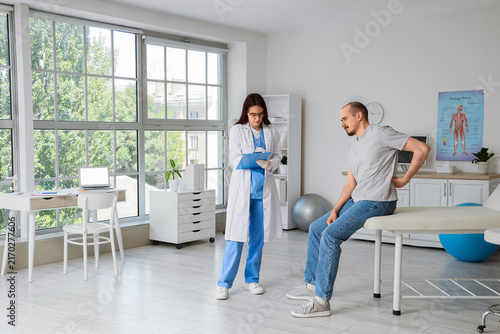 Back pain consultation and physical therapy, man with lower back discomfort t...