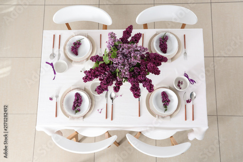 Beautiful table setting with lilac flowers in dining room