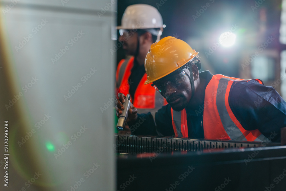 Fototapeta premium Technicians inspecting auto parts at liquid-filled station in auto parts factory