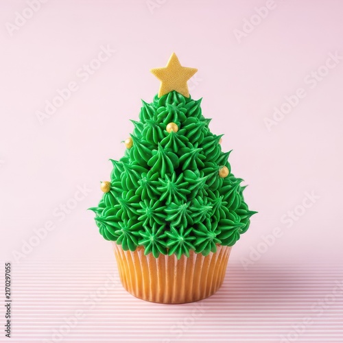 Creative Christmas tree cupcake featuring green icing and a gold star on a pink striped background with ample copy space for holiday text, studio, confectionery, bakery