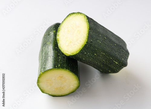 Konstfotografi Fresh green zucchini cut into half showing crisp inner flesh isolated on a white background