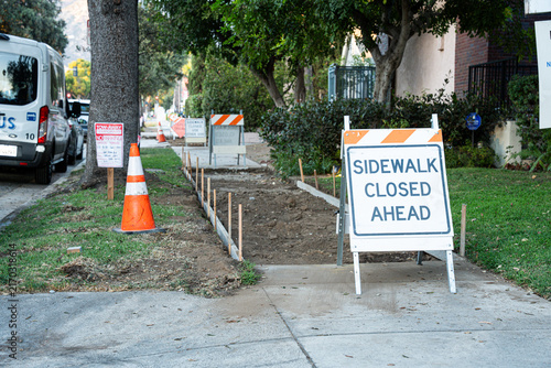 Fotografie Sidewalk construction ahead with detour signs and safety cones on the street