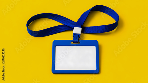 Blue ID card holder on bright yellow background, blank badge with lanyard, flat lay composition with copy space, corporate identification asset