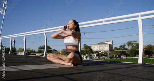 Yoga meditation. Lotus pose. Slim athletic female practicing breathing for mental health relaxing on bridge in summer park.