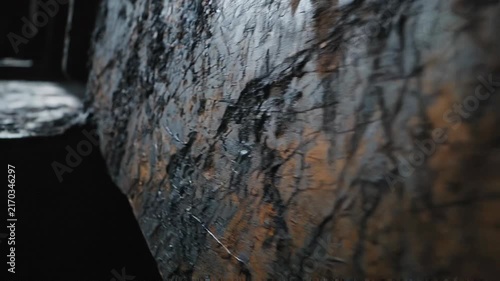 Close up of rough textured dark rock surface with natural patterns and details in low light environment
