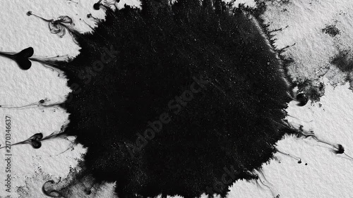 Black ink splash on white textured paper with artistic paint splatter effect