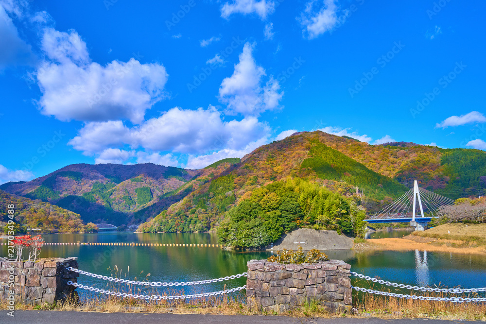 Fototapeta premium 紅葉の神奈川県山北町の三保ダムの天端道路(遊歩道)から北西側の眺望(永歳橋,ミツバ岳,世附大橋など)