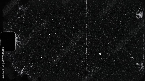 Close up of scratched and damaged vintage black film strip with dust particles and cracks on surface