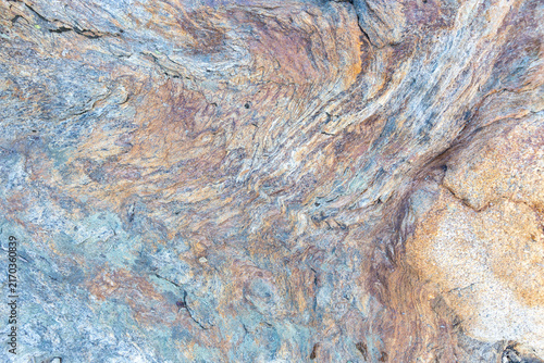 Macro shot of layered metamorphic stone texture showing rich brown and grey mineral veins in a natural wavy pattern, ideal for abstract wallpaper.