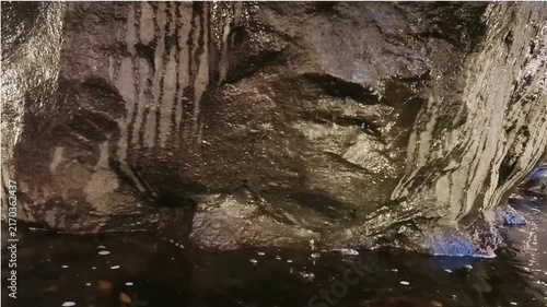 Water dripping down a dark cave rock wall