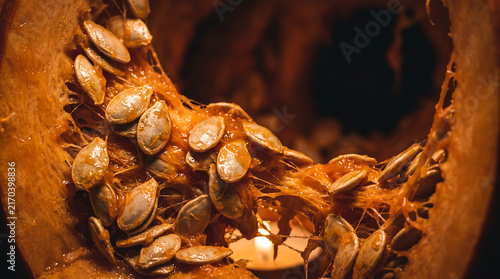 Fresh pumpkin seeds inside a carved jack-o-lantern for Halloween holiday preparation.