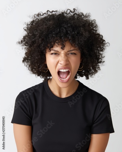 Young woman with curly hair yelling with angry facial expression