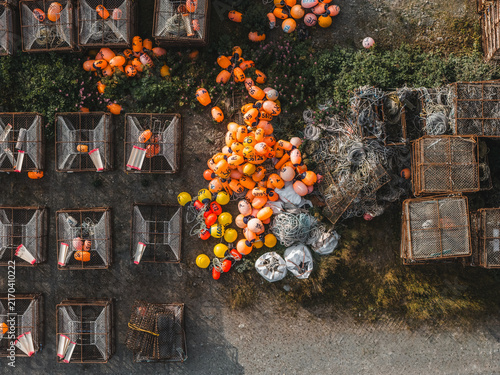 Aerial view of crab pots and colorful fishing buoys stacked on the ground in Unalaska, Alaska, United States.