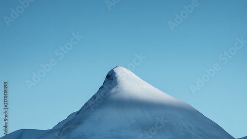 Snowy mountain peak reaching toward clear blue sky captured in bright natural daylight during winter season