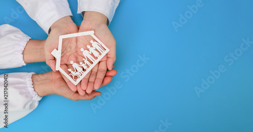 Fotografie Doctor hand holding paper house with family figure offers warm care, safety, pro