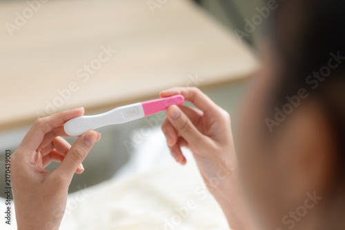 Картината върху платно Woman holding pregnancy test at home while checking the result, representing pregnancy, fertility, family planning, reproductive health and an important personal healthcare moment