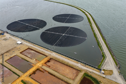 Aerial view of the floating solar farm at the PWN water treatment plant with circular solar arrays on the water surface in Andijk, Noord-Holland, Netherlands.