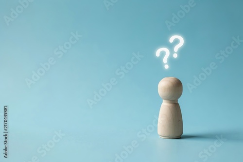 Wooden peg doll with question marks above head representing confusion or uncertainty thought bubble