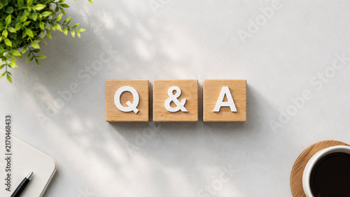 Top view of q and a wooden blocks on office desk with coffee and notebook.