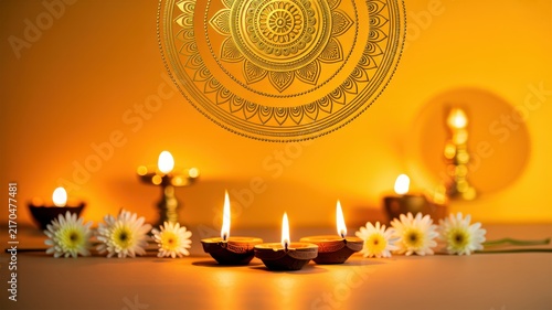 Happy Diwali Three glowing clay diya lamps with white daisy flowers on warm golden background for traditional Hindu Diwali festival celebration